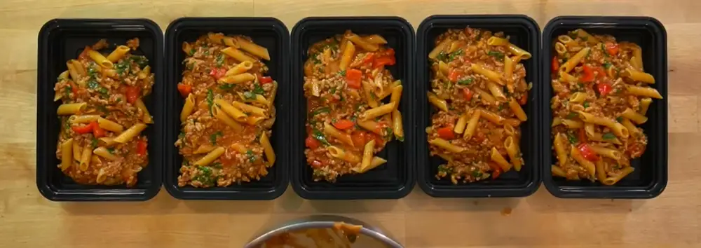 Cinco marmitas de macarrão com carne prontas, lado a lado